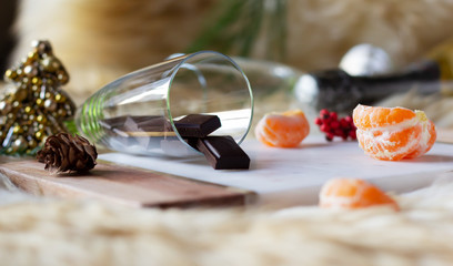 Mandarin pieces and dark chocolate bar in the champagne glass laid on the stone cutting board. Christmas and New Year composition. Winter festive mood