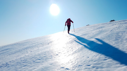 Mountaineer climbs a snowy mountain over blue clear sky. Winter season, sunny day. Concepts:...