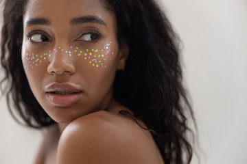 Cute Afro American woman with startling makeup posing for camera