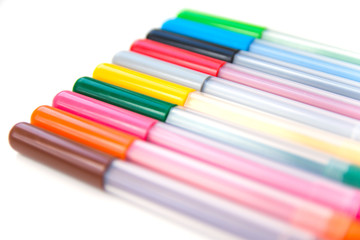 Opened colorful markers lying in a diagonal row on a white background. Isolated. Art and education. Selective focus.