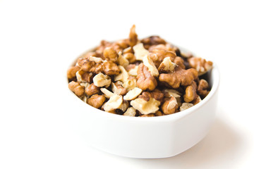 Peeled walnut kernels in white cup on white background. Healthy and organic food. Side view.