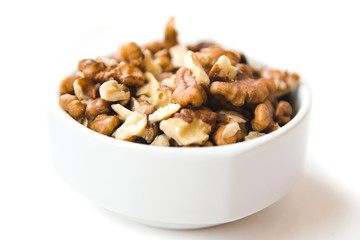 Peeled walnut kernels in white cup on white background. Healthy and organic food. Side view.