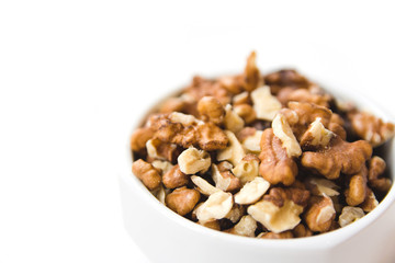 Peeled walnut kernels in white cup on white background. Healthy and organic food. Side view.
