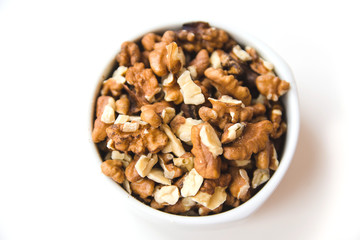 Peeled walnut kernels in white cup on white background. Healthy and organic food. Top view.