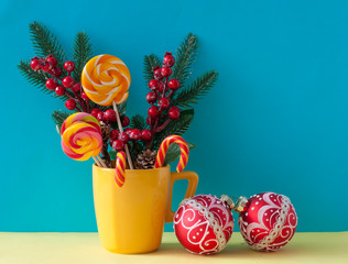 Christmas or new year card. Christmas decoratioration: Christmas candy canes in yellow mug with berries holly branches