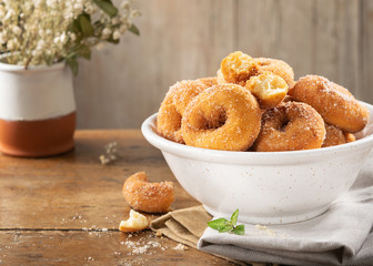 Closeup of a pile of homemade rosquillas, traditional homemade anise donuts from Spain, typically eaten in Easter, on a rustic wooden table, copy space.