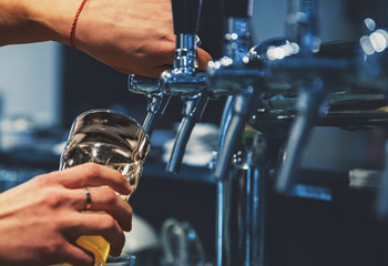 bartender hand at beer tap pouring a draught beer in glass serving in a restaurant or pub