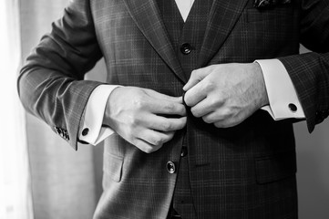 groom buckles the button on his jacket black and white