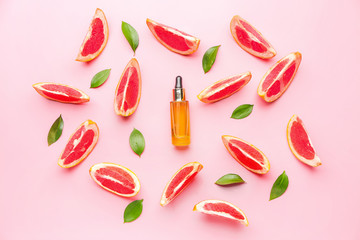 Bottle of essential oil and grapefruit slices on color background