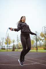 Active longhaired brunette girl jumping on skipping-rope