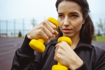 Attentive young female person training her strength