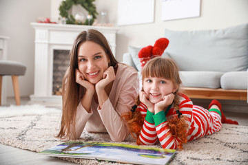 Little girl with mother reading book at home