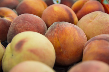 Delicious ripe and juicy peaches in box on a shelf in a vegetable store of supermarket. Organic farm and healthy food concept. Agriculture and harvesting. Selective focus.