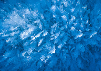 blue texture of an ice surface with pure azure water ,cold snow cryslallized wall background ,winter frozen lake side close up , abstract macro wallpaper