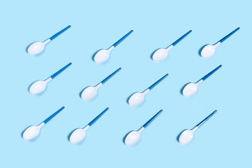 Group of white plastic spoons. Environmental problem of plastic rubbish pollution. Flat lay, top view, copy space.