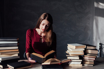 the girl sitting at the table reading a lot of books