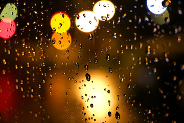 Rain droplets on glass at night withe colorful bokeh lights