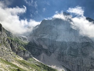 Beautiful view to the high mountains with small clouds on top misty sunshine hiking trail vista Mount Triglav slovenia