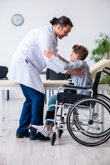 Fototapeta na wymiar Young male doctor pediatrist and boy in wheel-chair