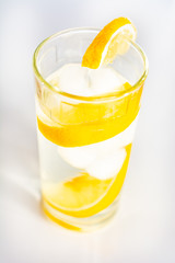 Glass of cold water with slices of ice and lemon.