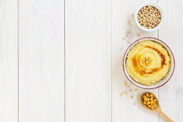 Hummus in a bowl on a wooden table. Horizontal orientation, copy space.