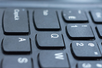 Modern black laptop keyboard closeup, english alphabet.