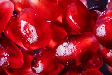 Ripe pomegranate seeds closeup on a dark background. Spectacular macro photo. The concept of wholesome organic food, vegetarianism, fresh fruit harvest.