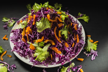 head lettuce bell pepper red cabbage salad casually scattered around a flat dish. black bacround. horizontal.