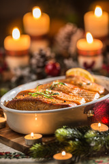 Christmas dinner from fish salmon in roasting dish with festive decoration advent wreath and candles.