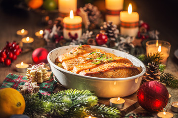 Christmas dinner from fish salmon in roasting dish with festive decoration advent wreath and...