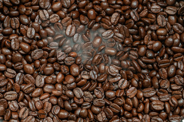 Roasted coffee beans with smoke close-up