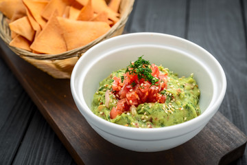 A delicious authentic mexican guacamole dip with avocado, lime, and tomato.