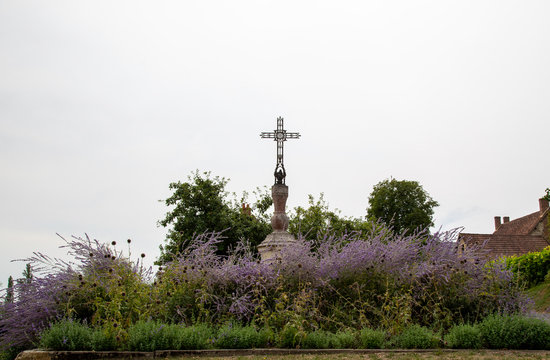 detail of rural French village cross with purple planting isolated against a white sky