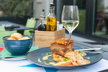 Roasted pork belly meat served with glass of white wine