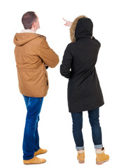 Back view of couple couple in winter jackets pointing.