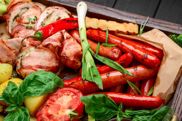 dish with grilled meat set of beef, pork, chicken, sausages and vegetables at decorated table background.