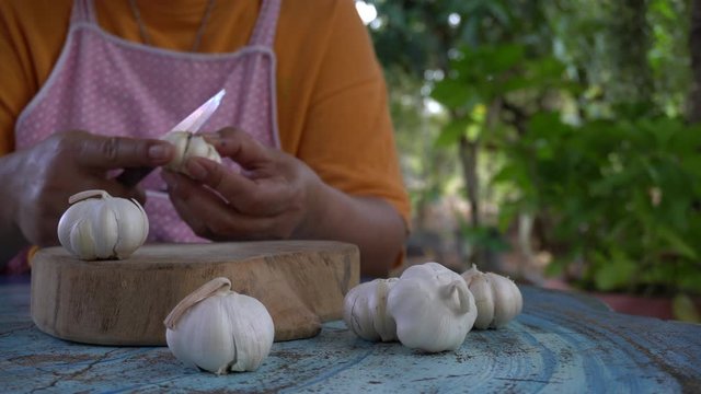 women garlic peeling on wood cutting board. women preparing to cook on the blue table, natural atmosphere.