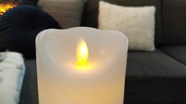 Candle flame close up on home cozy background. Electronic simulation