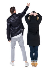 Back view of couple couple in winter jackets pointing.