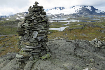Troll stone tower in front of the beautiful mountain and tundra landscape with snow dots and little laeks on the Snovegen "the snow street" , the Aurlandsfjellet, a scenic route between Laerdal and Au