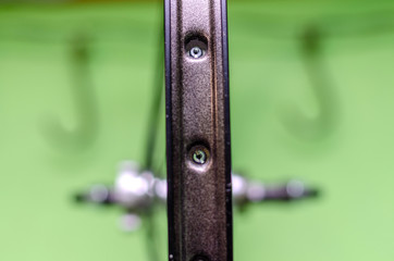 Bicycle repair workshop. On the hook hang new wheels. The hub is black and the spokes and rim are silver. The old bike here is gets a second chance. Parts close-up.