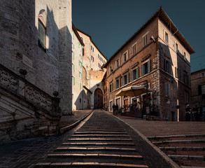 Fototapeta na wymiar The streets of the old city are flooded with sun. Stairs of the old city of Perugia. Umbria Italy.