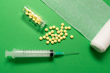 Syringe with pills for injection and vaccination on green background with bandage, concept of...