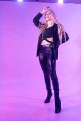 Attractive blonde woman sitting on the chair over pink background