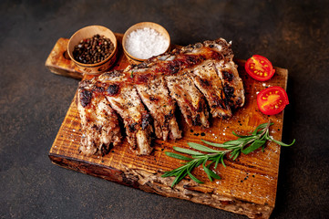 Grilled pork ribs with spices on a cutting board on a stone background 