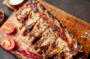 Grilled pork ribs with spices on a cutting board on a stone background 
