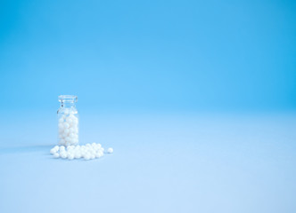 Homeopathy globules in glass bottles on a blue background. Alternative homeopathy herbal medicine,...
