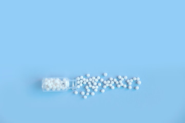 Homeopathy globules in glass bottles on a blue background. Alternative homeopathy herbal medicine, pills. Copyspace for text.
