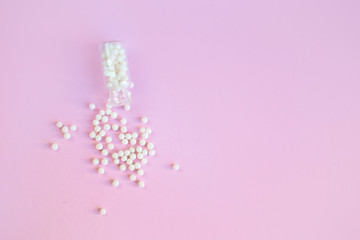 Homeopathy globules in glass bottles on a pink background. Alternative homeopathy herbal medicine, pills. Copyspace for text.