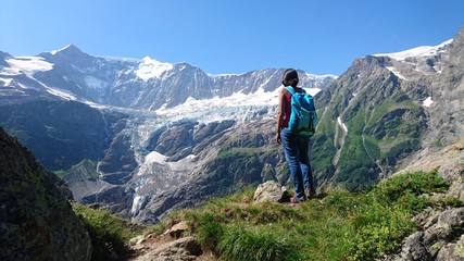 Fototapeta na wymiar Hiker woman girl with backpack enjoying the mountains scenic view and the glaciers high alpine mountain trail climbing rest meditation switzerland